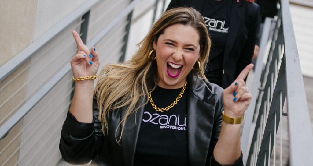 Michelle smiling at the camera, holding up two fingers on each hand, giving the peace sign.