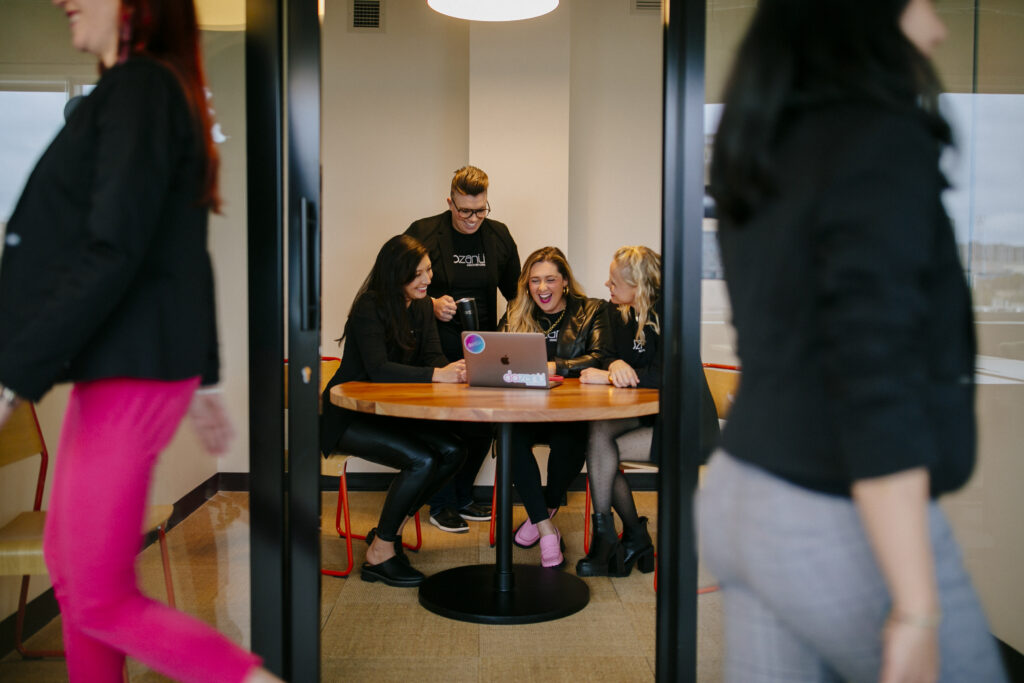 The dozanü team sitting around a table working on a laptop.