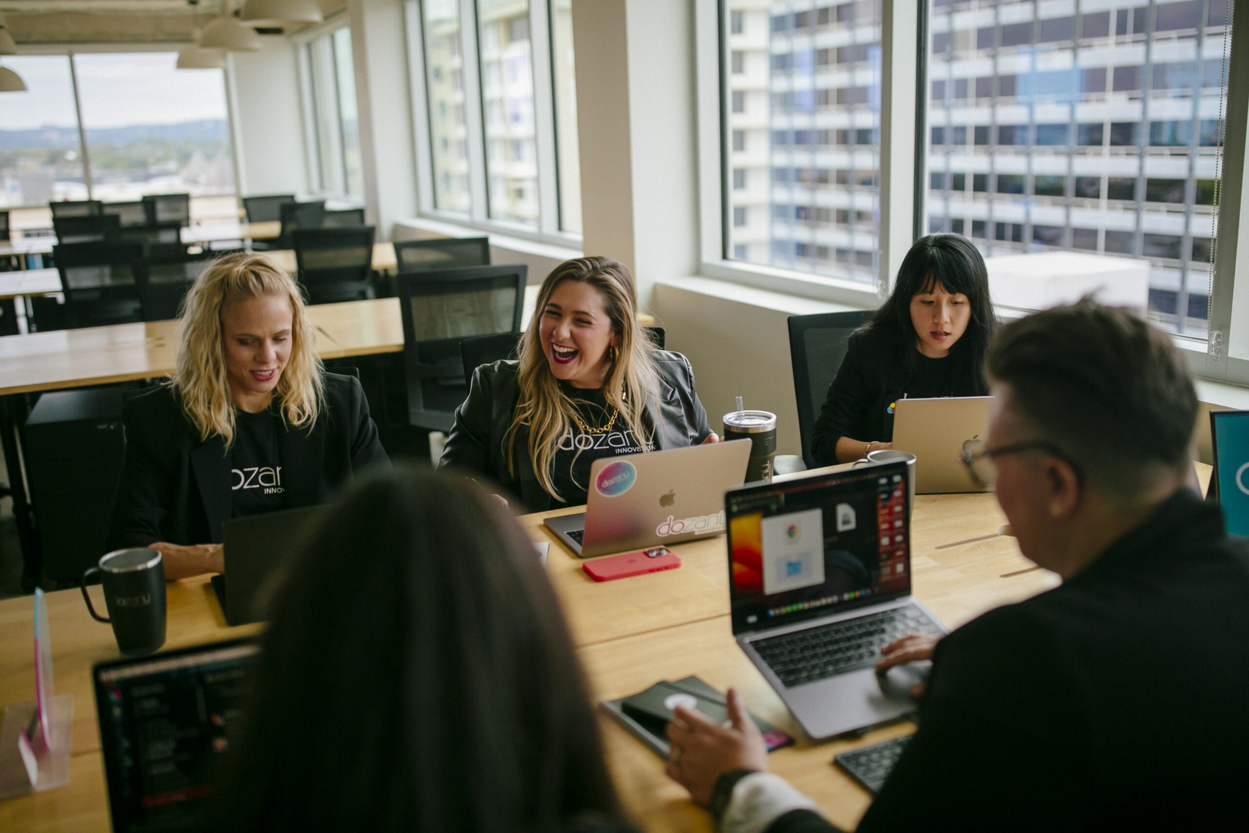 The dozanü team sitting at a long table working on their laptops.